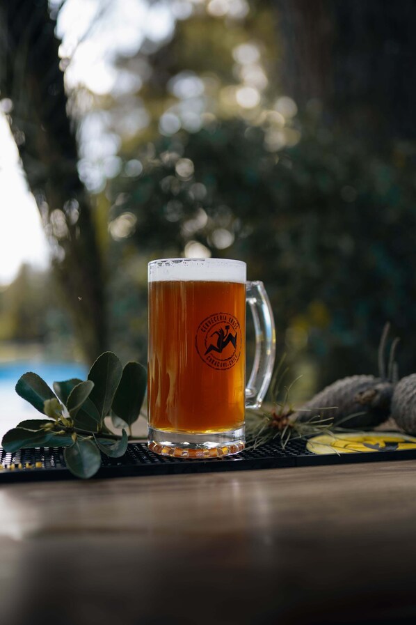 A glass of beer on a table with a logo, surrounded by greenery. - Complejo Turístico Valle del Sol Quillón (Quillón)