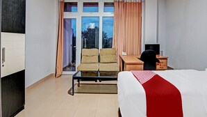 A hotel room with a bed, a desk, a chair, and a window with curtains. - OYO 91951 Almira Homestay Syariah (Pekanbaru)