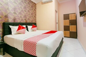 Una habitación de hotel con una cama grande, un muro con estampado geométrico y un armario de madera.