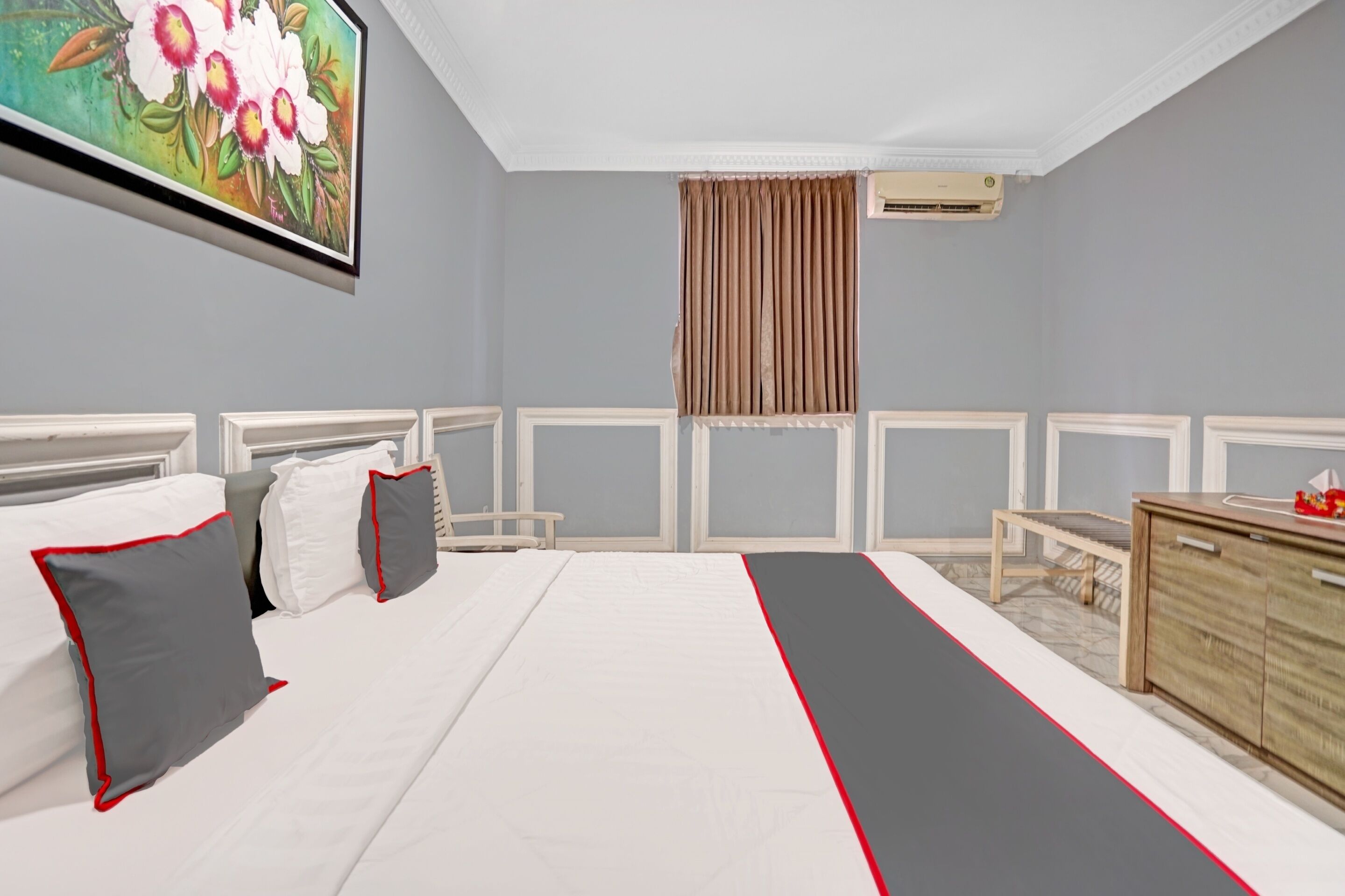 Een slaapkamer met een bed, nachtkastjes, een kaptafel en een schilderij aan de muur.