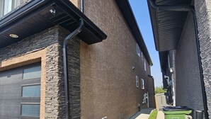 A residential building with a garage, stone facade, and a green dumpster. - Cozy Suite: Private and peaceful 2 bedroom basement suite with keyless entry  (Edmonton)