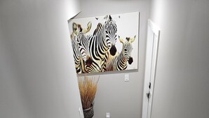 A staircase with wooden steps and white walls, leading to a door with a zebra mural on the wall. - Cozy Suite: Private and peaceful 2 bedroom basement suite with keyless entry  (Edmonton)