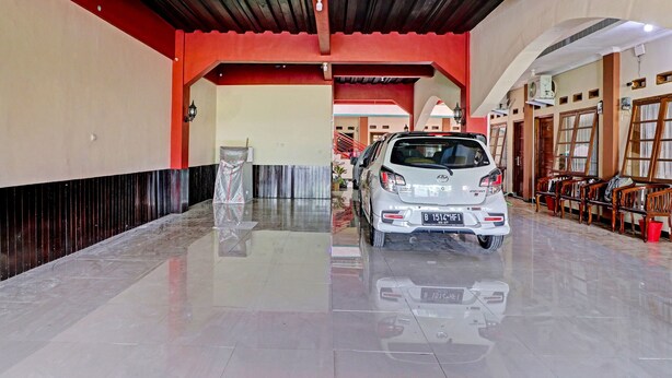 A car parked in a well-lit, spacious indoor area with a polished floor, a red ceiling, and wooden furniture. - OYO Life 91480 Putridapisa Syariah (Sumedang)