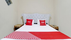 A neatly made bed with a red and white patterned bedspread and two red pillows with the word "OYO" on them. - OYO Life 91480 Putridapisa Syariah (Sumedang)