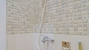A shower with a handheld hose and a wall-mounted faucet. - OYO Life 91480 Putridapisa Syariah (Sumedang)