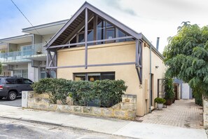 Stylish two-story home with a gable roof and large windows, featuring a garden area and a comfortable living space.