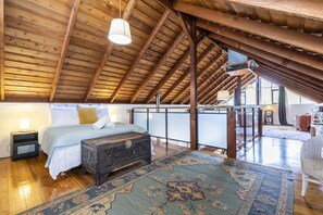 Cozy attic retreat with a large bed, wooden chest, and traditional rug.