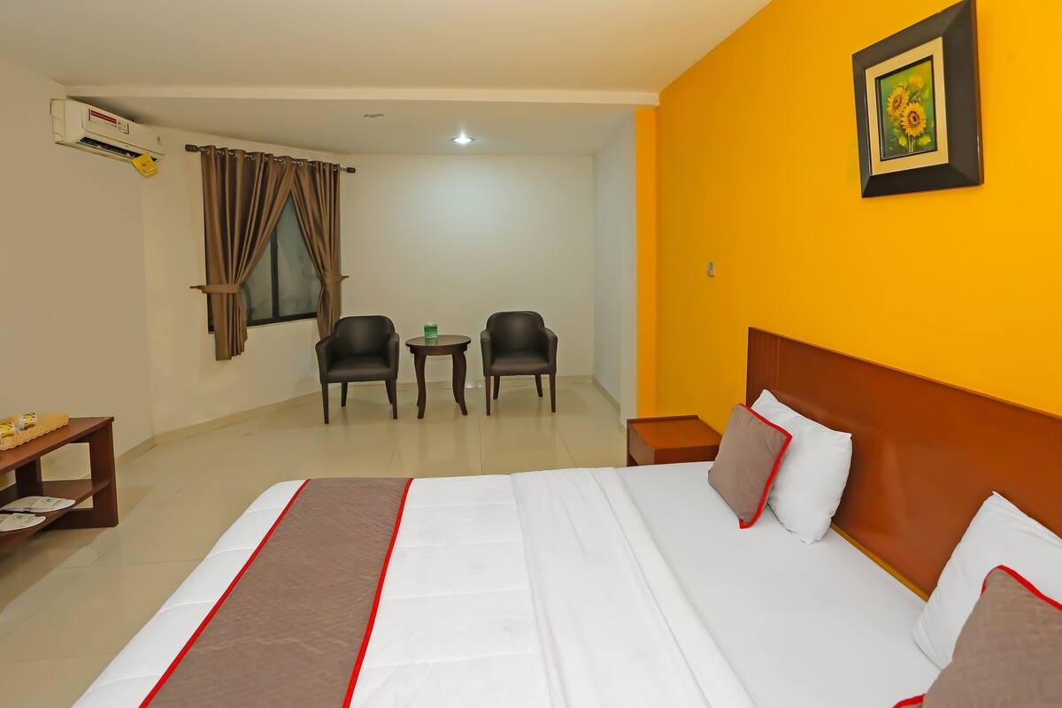 Une chambre d’hôtel comprenant un lit, deux chaises, une petite table et un appareil de climatisation.