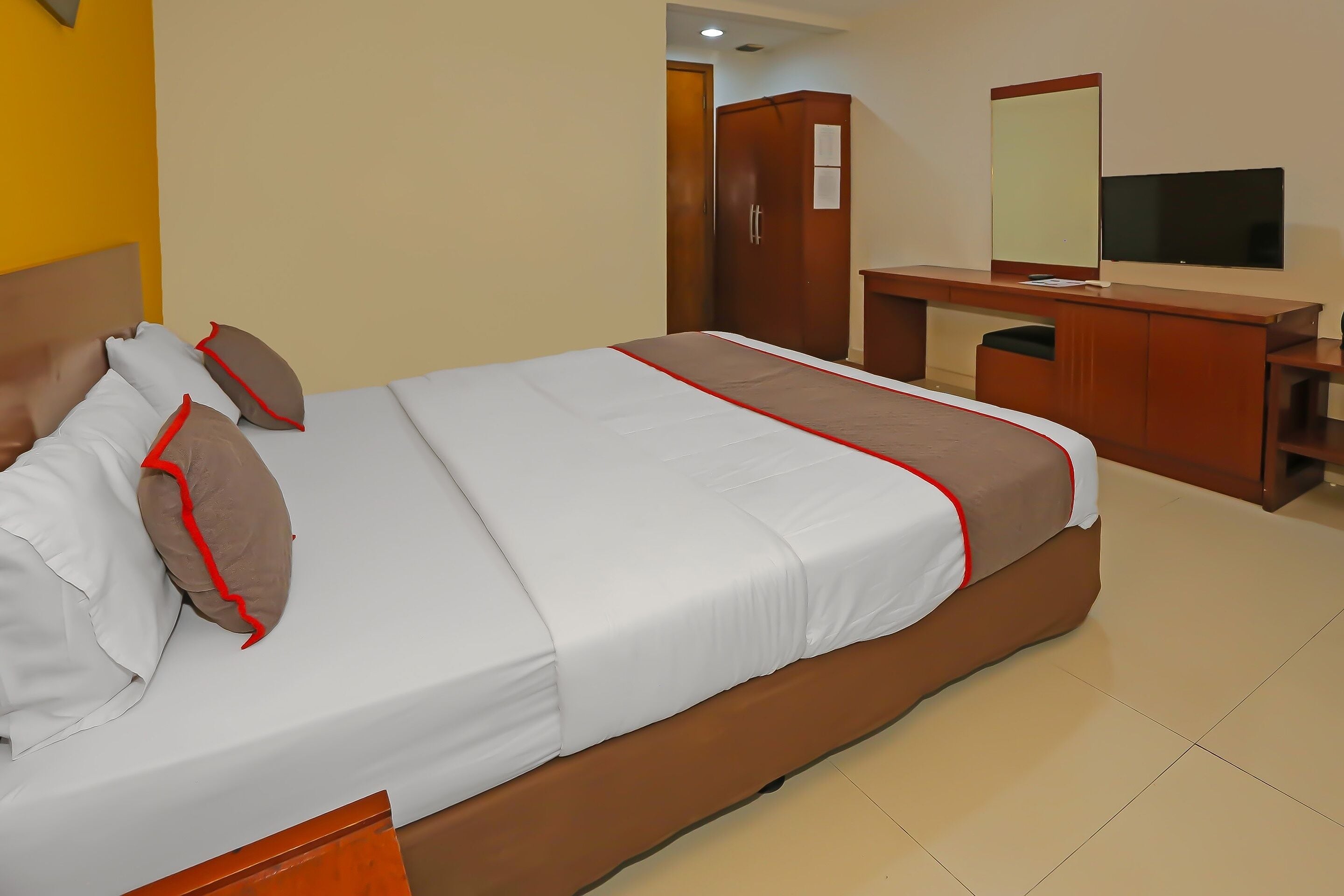Ein Hotelzimmer mit einem Bett, einem Holzschrank, einem Schreibtisch und einem Fernseher.