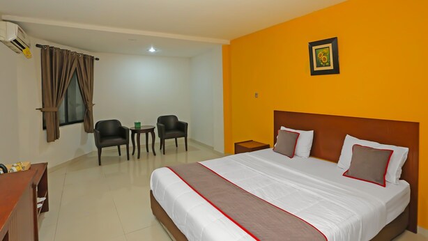 A hotel room with a large bed, a desk, two chairs, and a small table. - Townhouse OAK Hotel Fiducia Pasar Minggu (Jakarta)