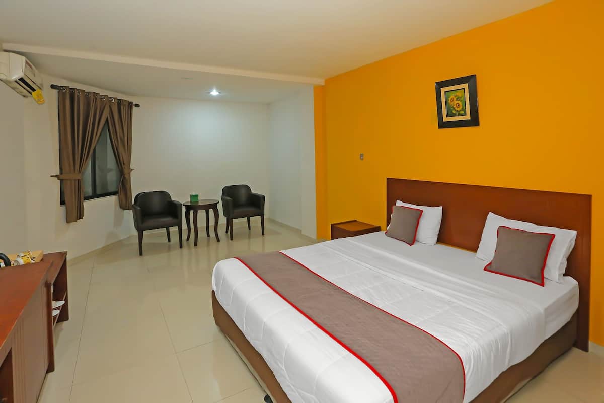 Une chambre d’hôtel avec un grand lit, un bureau, deux chaises et une petite table.