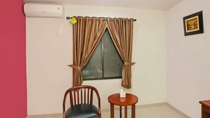 A room with a window, a chair, a small table, and an air conditioning unit. - Townhouse OAK Hotel Fiducia Pasar Minggu (Jakarta)
