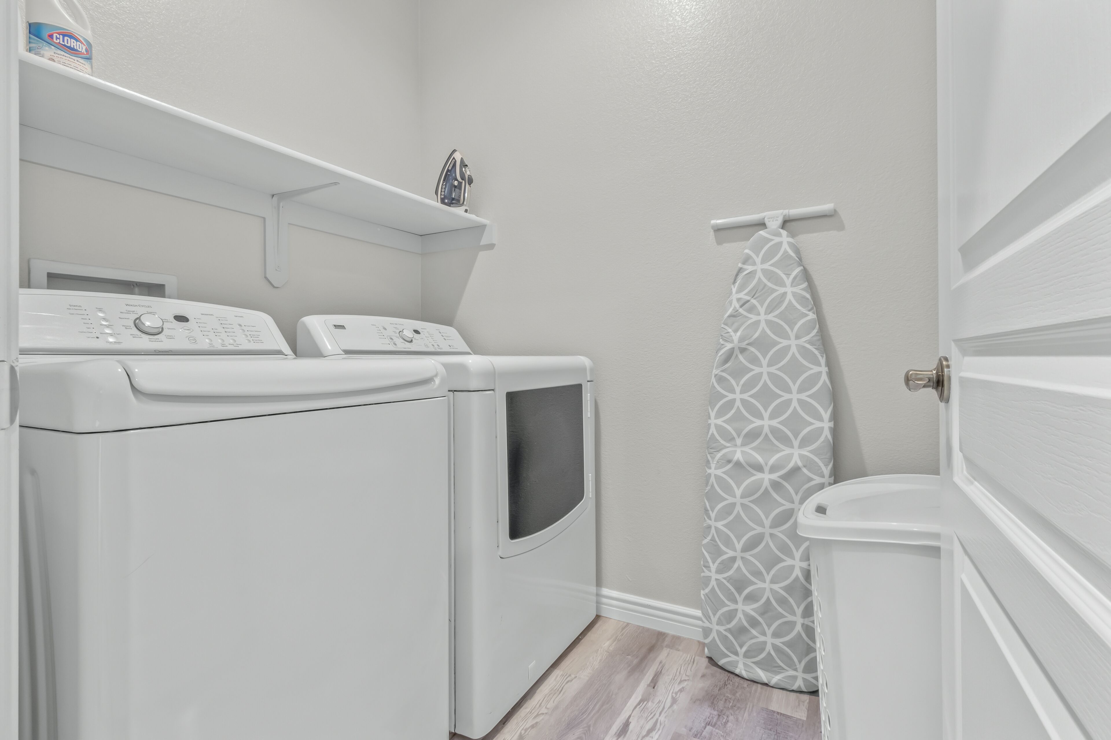 A laundry area with a washing machine, dryer, and ironing board.