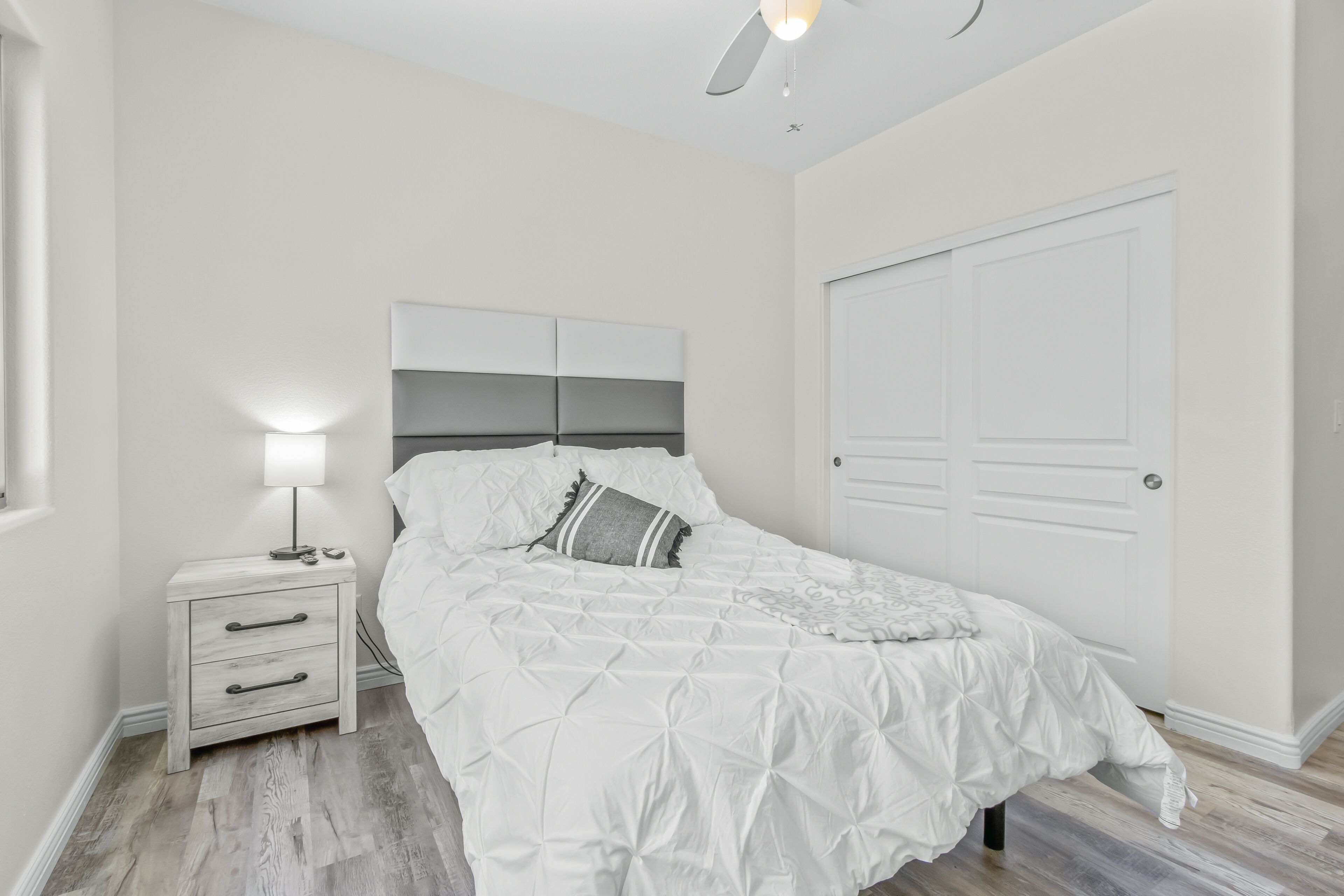 Un dormitorio con cama, mesita de noche y una puerta cerrada.
