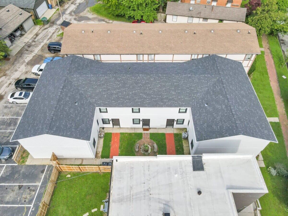 A multi-story building with a flat roof, a central courtyard with a fountain, and a parking lot.