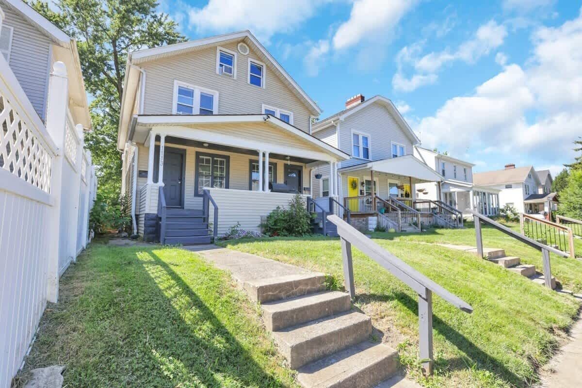 A residential property with a front porch, a staircase, and a well-maintained lawn.