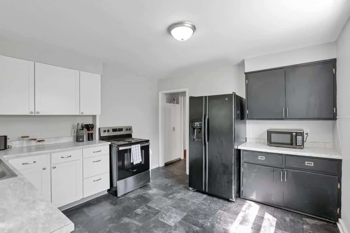 A modern kitchen with white cabinets, a stainless steel refrigerator, a microwave, and a stove.