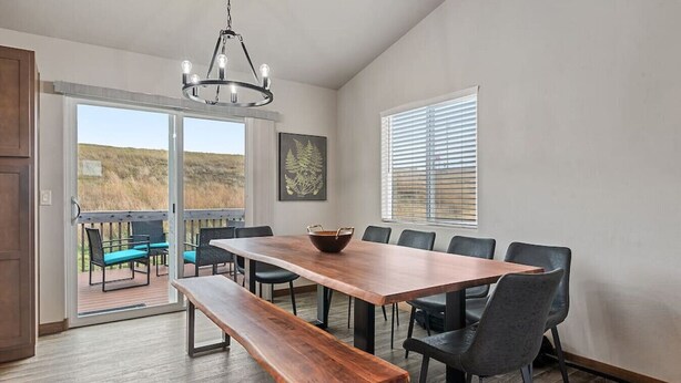 Een eetgedeelte met een grote houten tafel, zes stoelen, een bank en een kroonluchter.