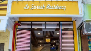 The entrance to Le Suresh Residency with a yellow facade and a sign above the entrance. - Le Suresh Residency (Puducherry)