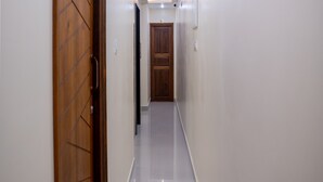 A hallway with wooden doors and white walls, leading to a room with a door marked "303". - Le Suresh Residency (Puducherry)