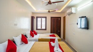 A hotel room with two beds, red and white bedding, a ceiling fan, an air conditioning unit, and a television on the wall. - Le Suresh Residency (Puducherry)