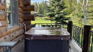 A log cabin with a hot tub on the porch, a table, and a bench. - Tweek's Cabin- luxury cabin with yard, fire pit, and hot tub!!!

 (Cody)