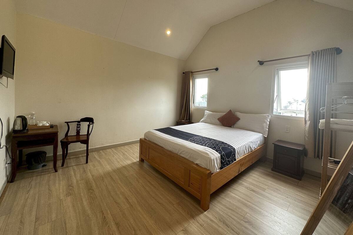 Un dormitorio con una cama de madera, un escritorio con una silla, un radiador y una ventana con cortinas.