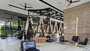 A modern hotel lobby with a geometric partition, leather seating, and ceiling fans. - Expressionz Premium Suites at KLCC (Kuala Lumpur)