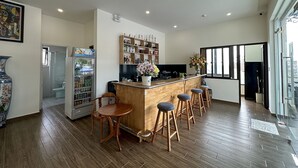 Een moderne keuken met een houten bar en krukken, een koelkast en een douchecabine van glas.
