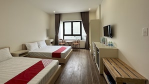 Een hotelkamer met twee bedden, een bureau, een stoel, een televisie en een houten bank.