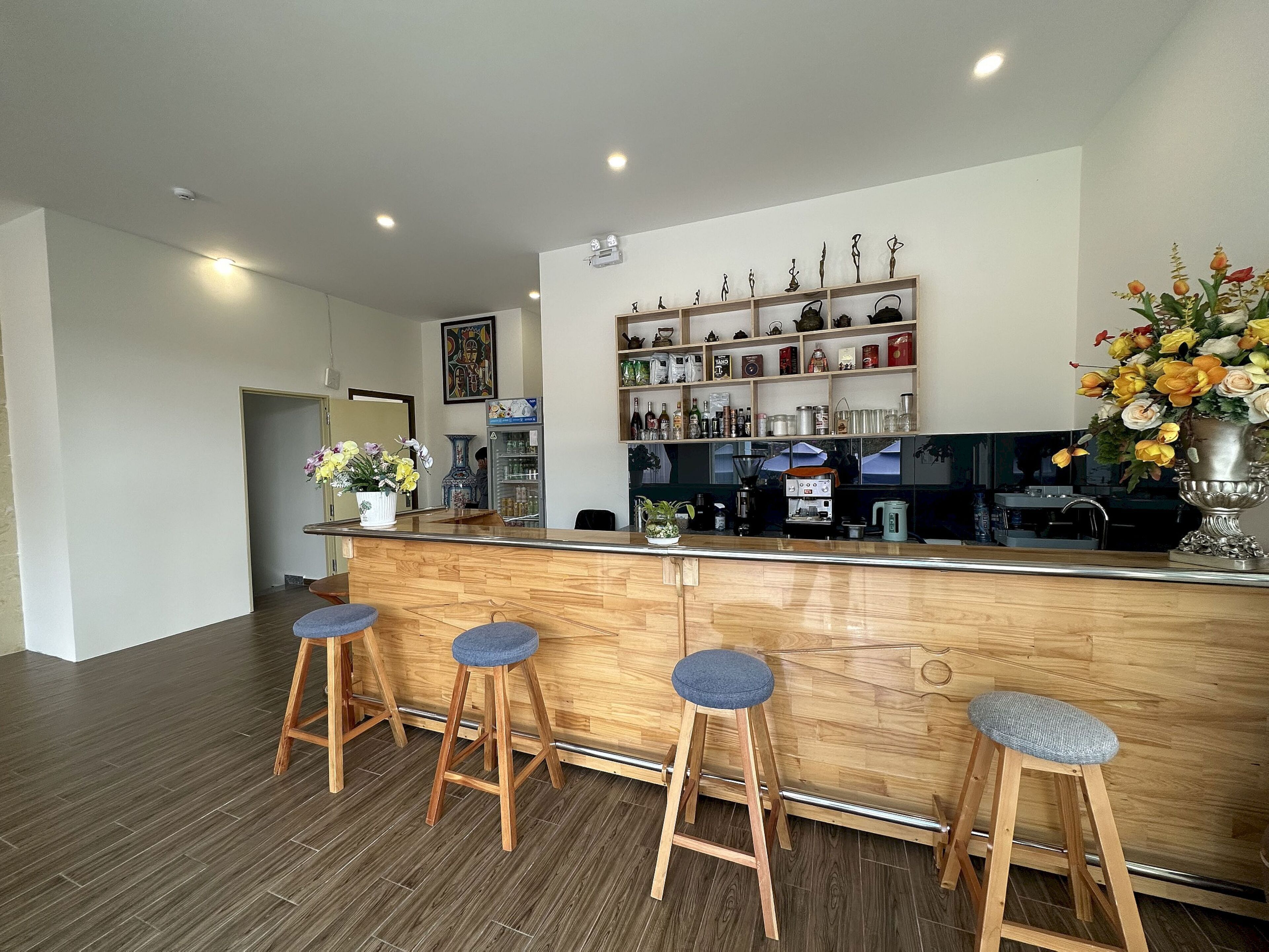 A bar area with wooden stools, a counter, and shelves with various items.