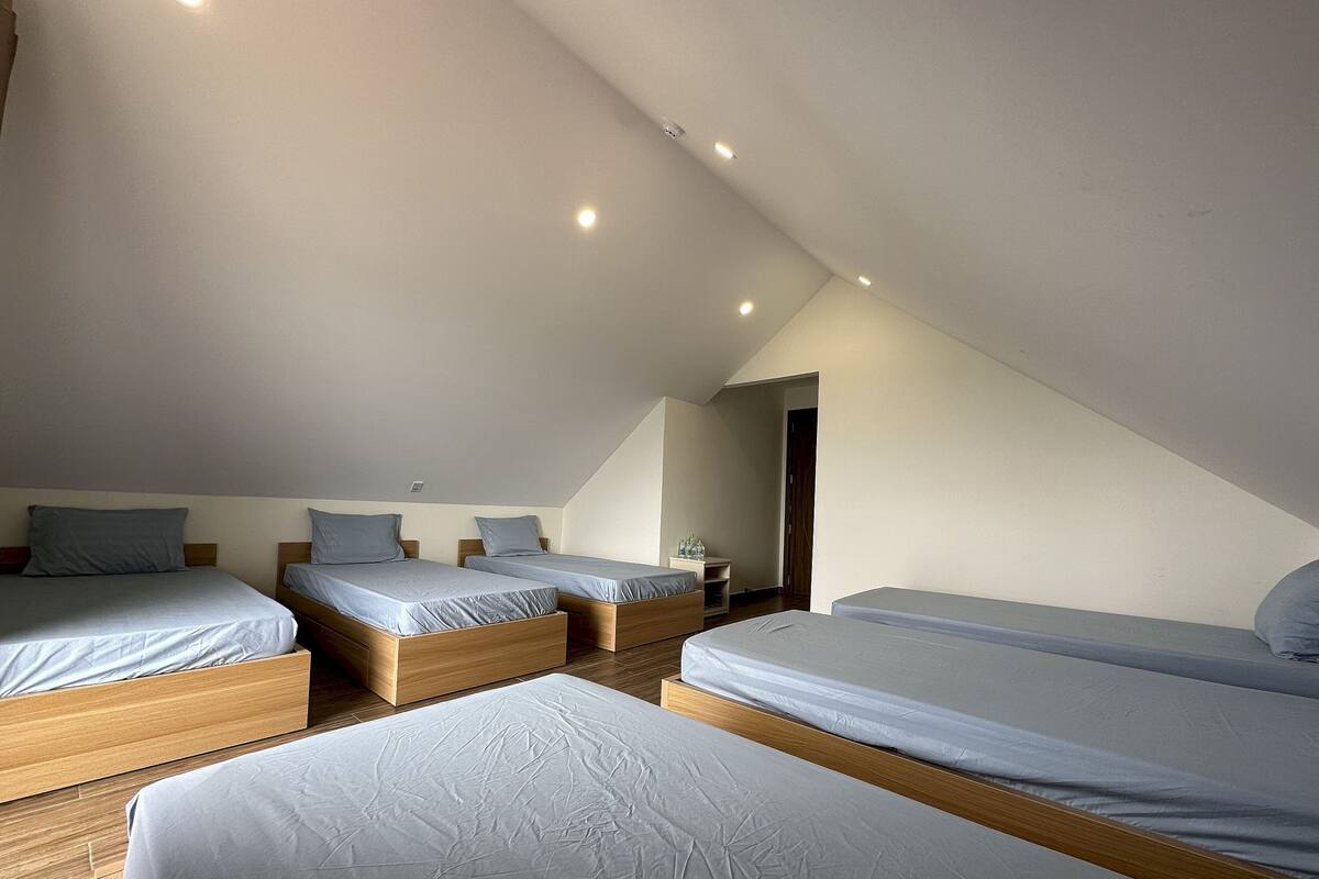 A bedroom with three single beds, wooden headboards, and a sloped ceiling.