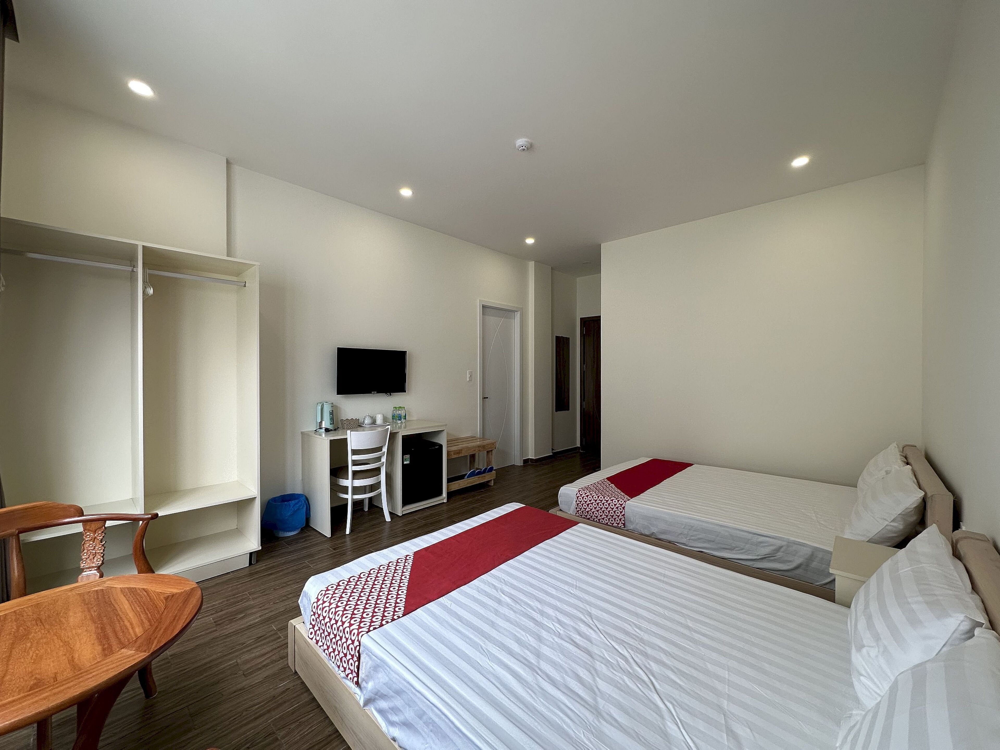 A hotel room with two beds, a desk with a chair, a television, and a wardrobe.