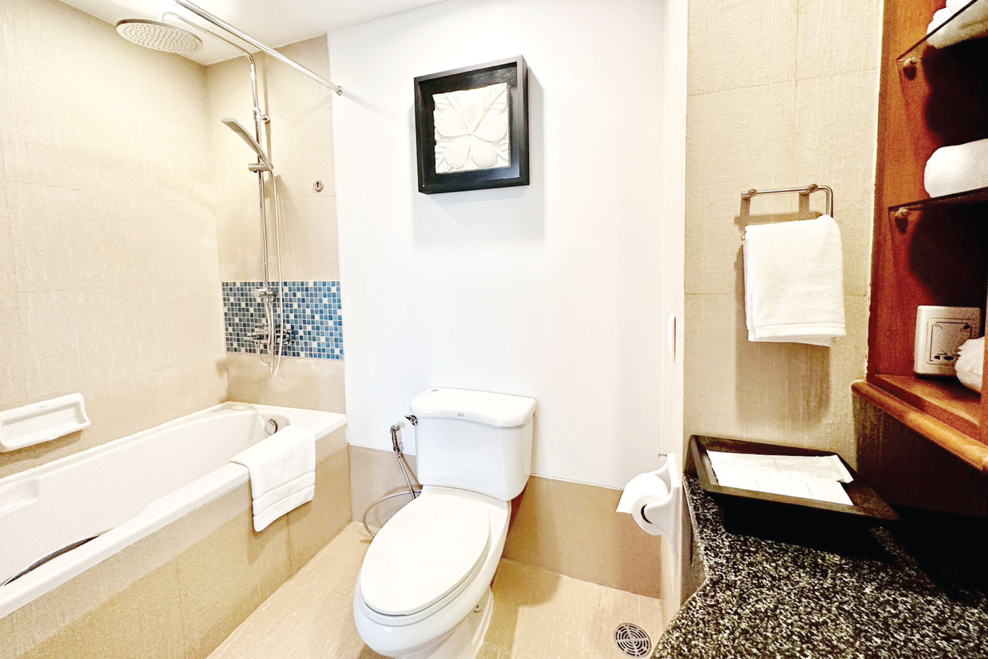 A bathroom with a bathtub, toilet, shower, and a framed artwork on the wall.