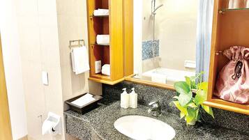 Un baño con lavamanos de encimera de granito, un espejo, ducha y toallero.
