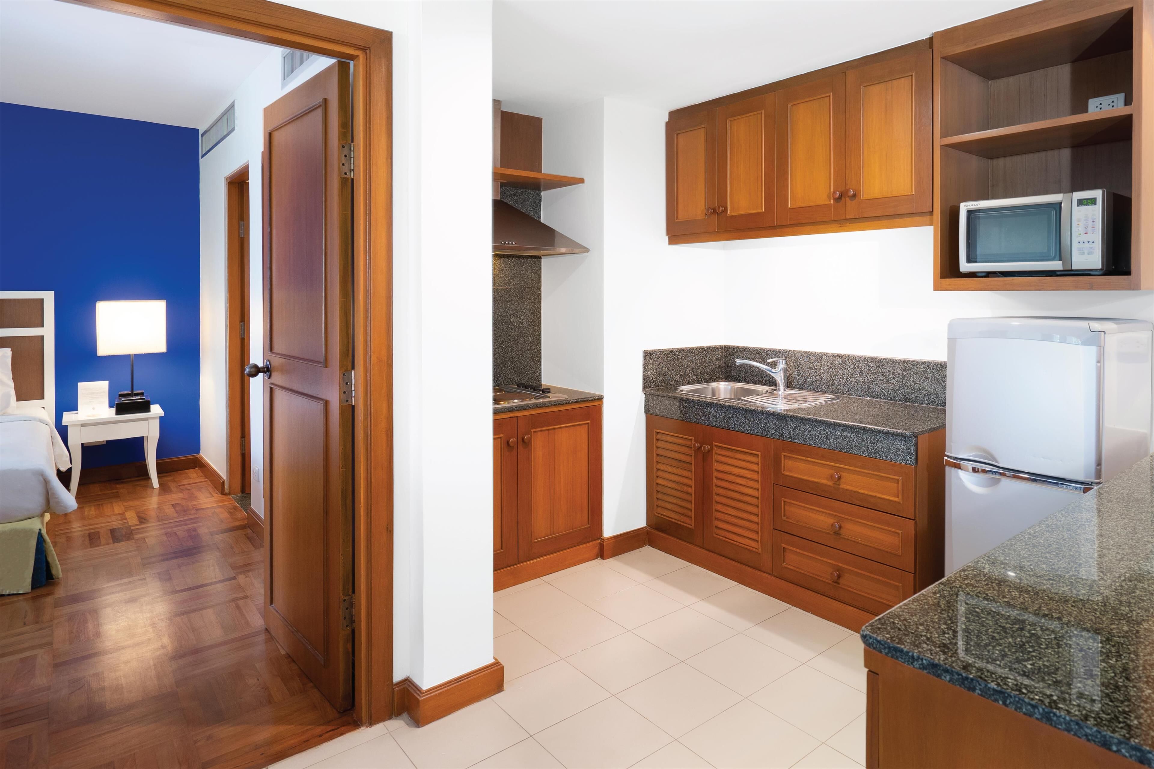 Una cocina compacta con armarios de madera, encimera de granito, microondas y refrigerador.