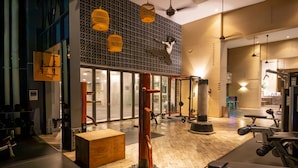 A gym with various exercise equipment, wooden flooring, and patterned wall decor.