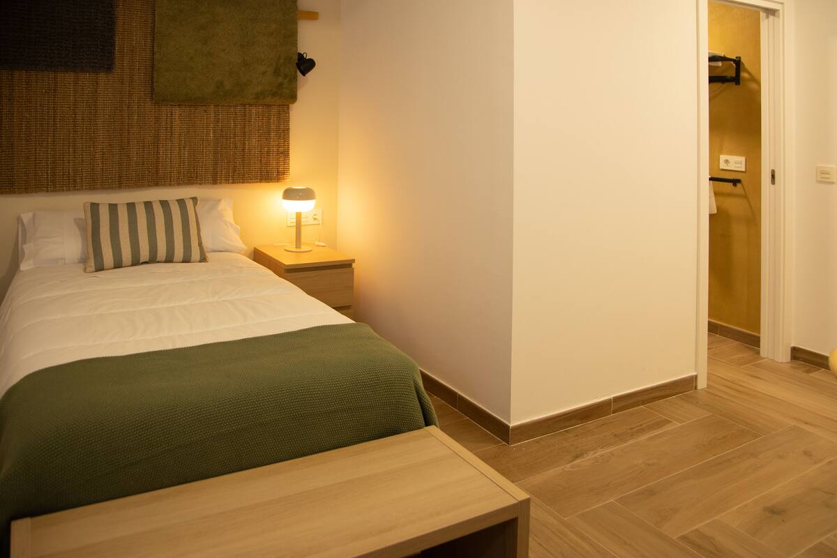 A neatly arranged bedroom with a bed, bedside table, and a lamp.