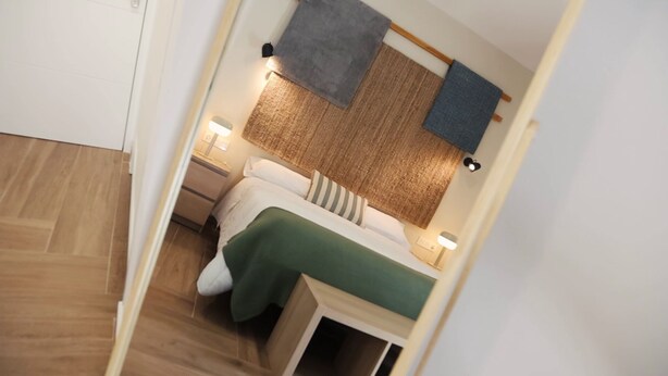 Un dormitorio acogedor con cama, mesitas de noche y cabecero con textura tejida.