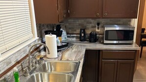 A kitchen with a stainless steel sink, a microwave, and a fire extinguisher. - remodeled home-Montgomery,AL: Auburn, Tuskegee. Troy, and ASU -high schools (Montgomery)