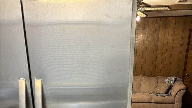 A stainless steel refrigerator in a kitchen with wooden flooring and a beige sofa in the background. - remodeled home-Montgomery,AL: Auburn, Tuskegee. Troy, and ASU -high schools (Montgomery)