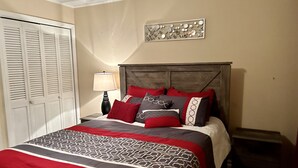 A bedroom with a bed, a nightstand, a lamp, a wall art piece, and a closet. - remodeled home-Montgomery,AL: Auburn, Tuskegee. Troy, and ASU -high schools (Montgomery)