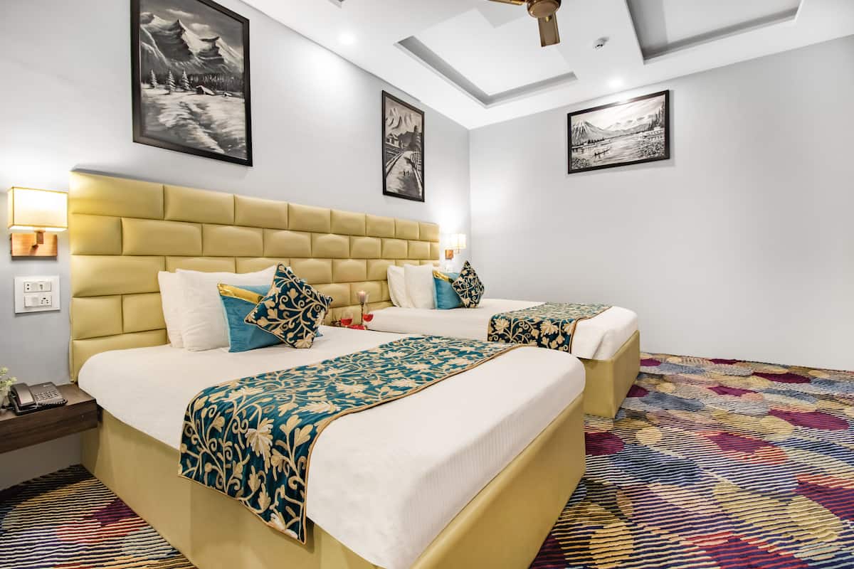 A hotel room with two beds, a patterned rug, and artwork on the walls.