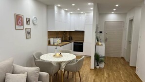 Um apartamento moderno com área de jantar, cozinha e sala de estar com sofá.