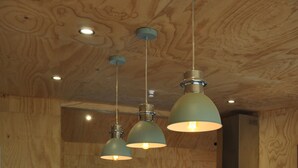 A modern kitchen with wooden cabinetry, a large island, and pendant lighting. - Renagour Cottage - Rural charm with outdoor hot tub! (Mangamahu)