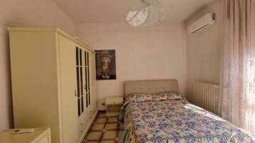A bedroom with a bed, a wardrobe, a poster, and a radiator.