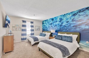 A hotel room with two beds, a large ocean-themed mural, a wooden dresser, and a television on the wall. - 8 Bdrm Mansion 10 Mn To Honeymoon Island Beach (Palm Harbor)