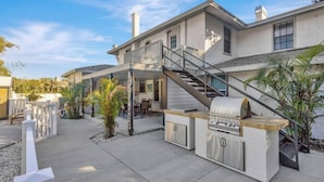 A modern house with a covered patio, outdoor kitchen, and a staircase leading to an upper level. - 8 Bdrm Mansion 10 Mn To Honeymoon Island Beach (Palm Harbor)