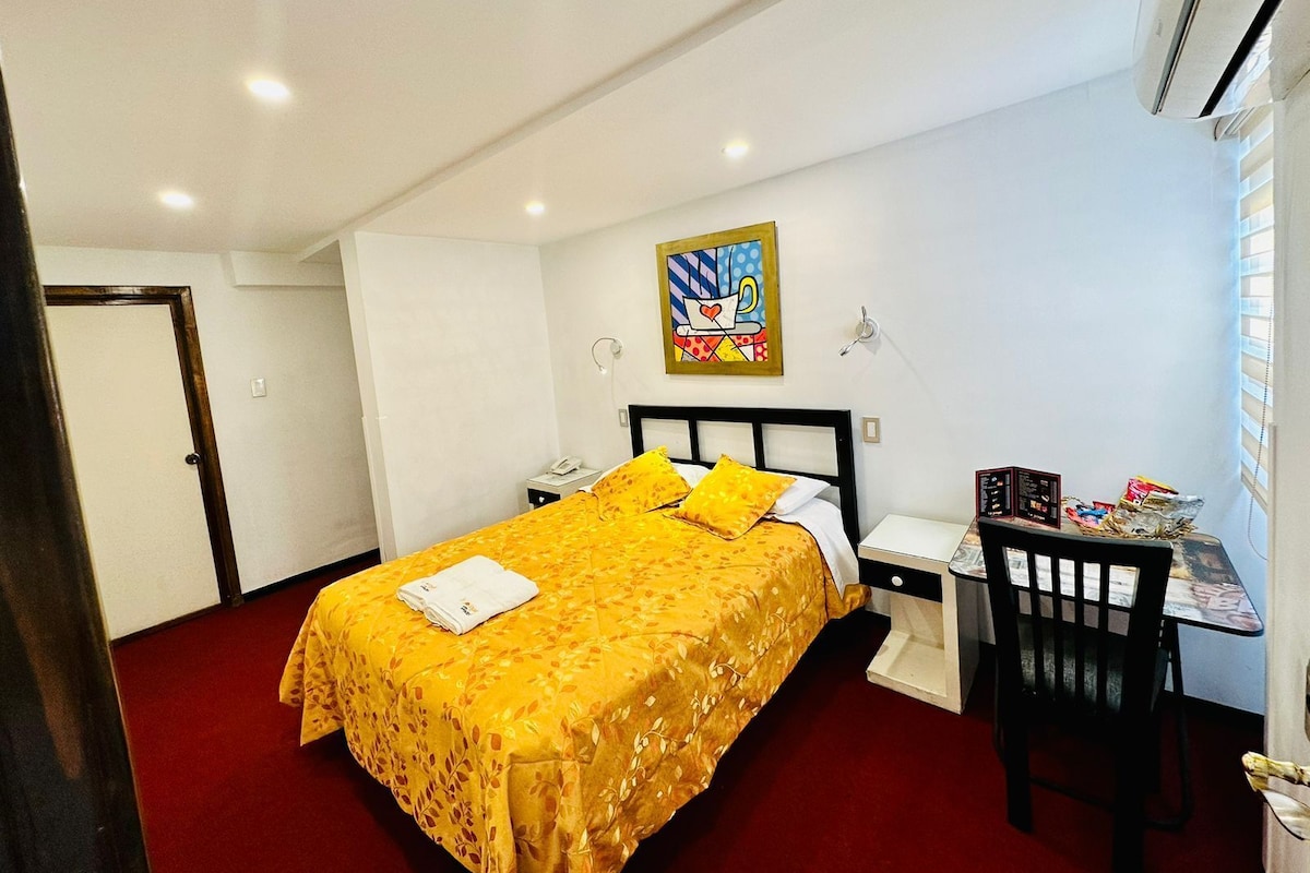 A hotel room with a bed, a desk, and a chair.