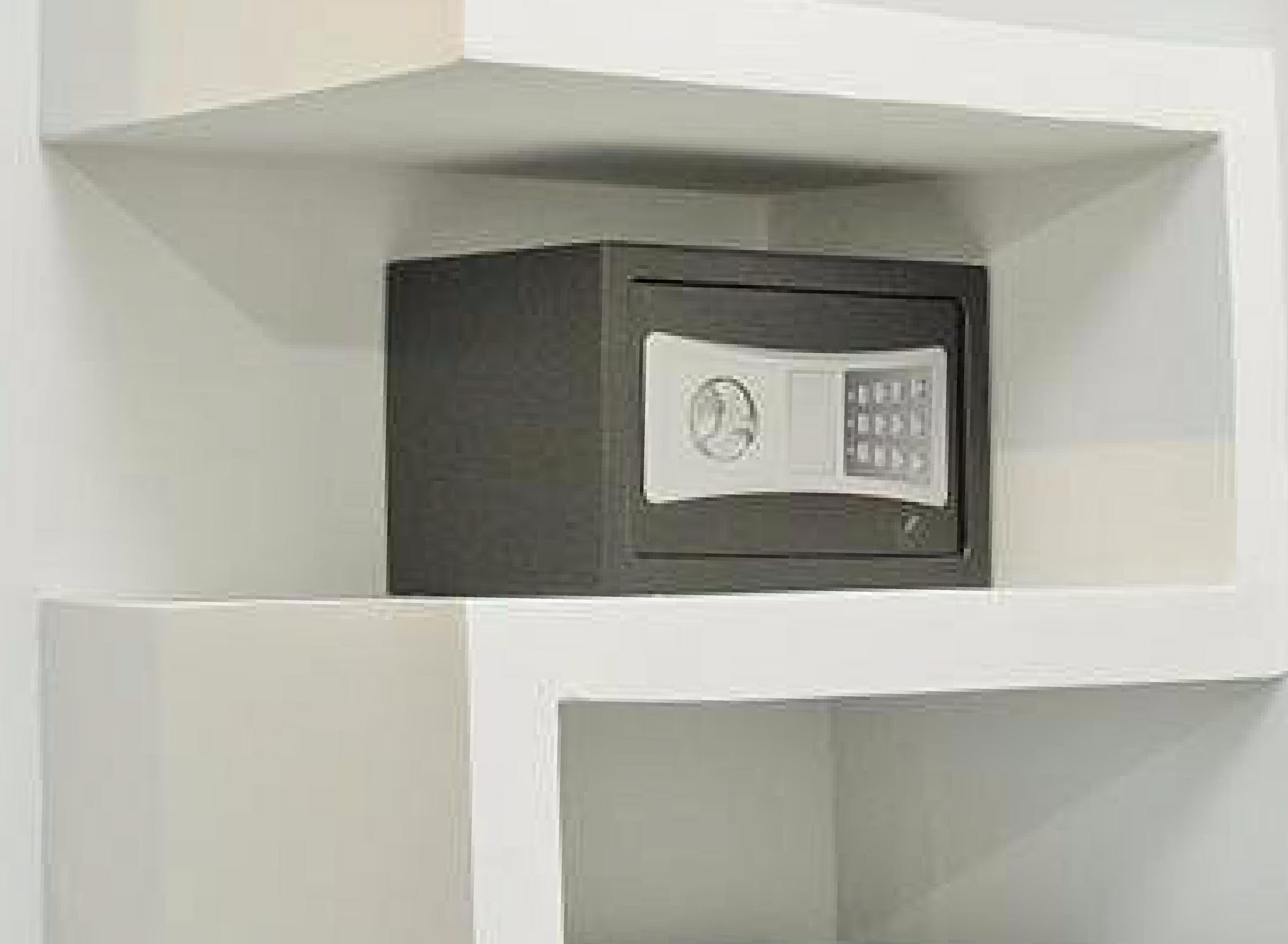 Un armadietto di sicurezza con serratura a combinazione, all'interno di un mobile contenitore bianco.